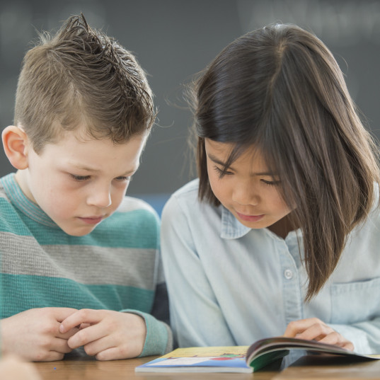 Elementary school students read together in class.